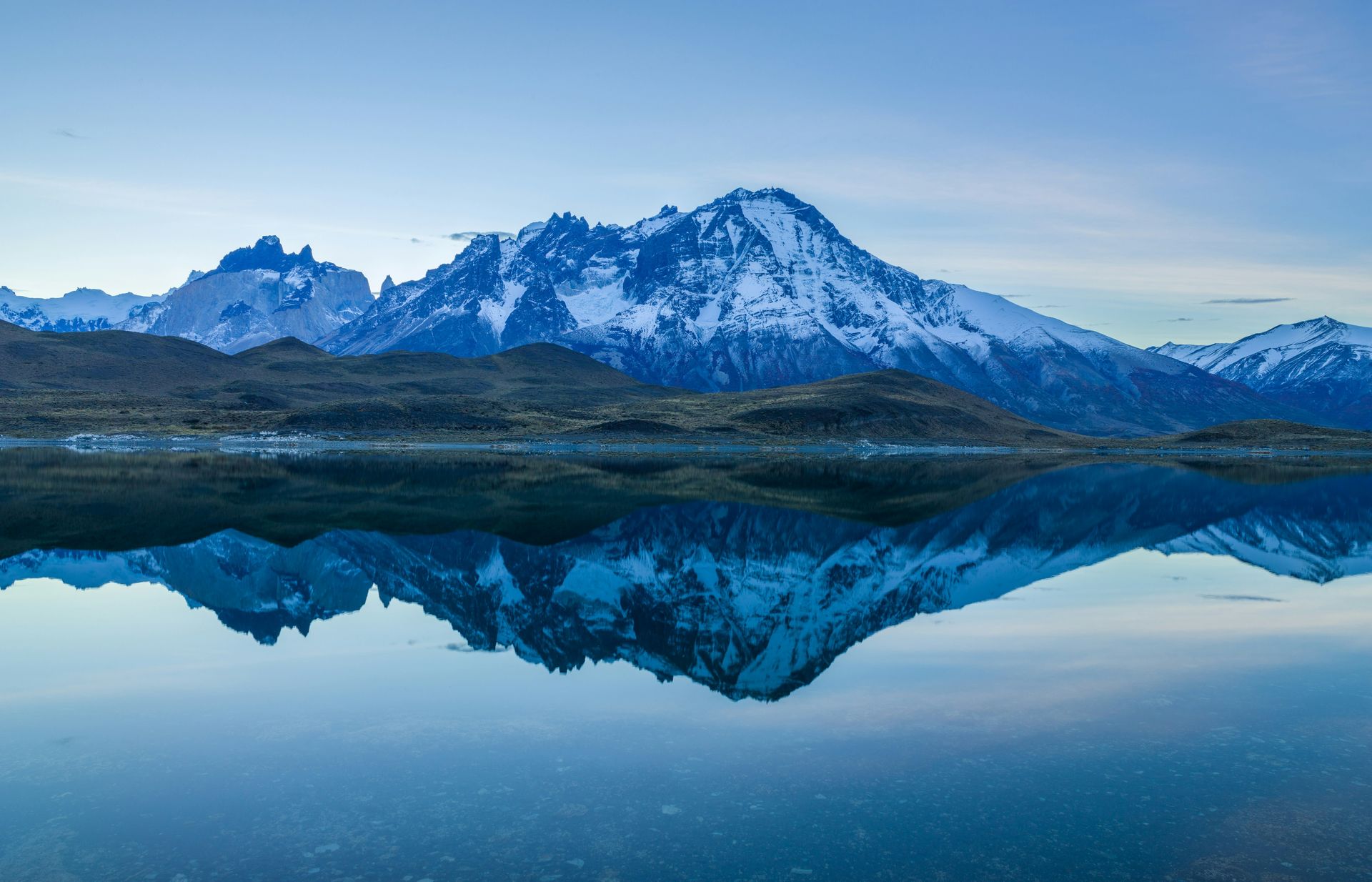 Snow-capped mountain peaks reflected in a still lake at dusk
