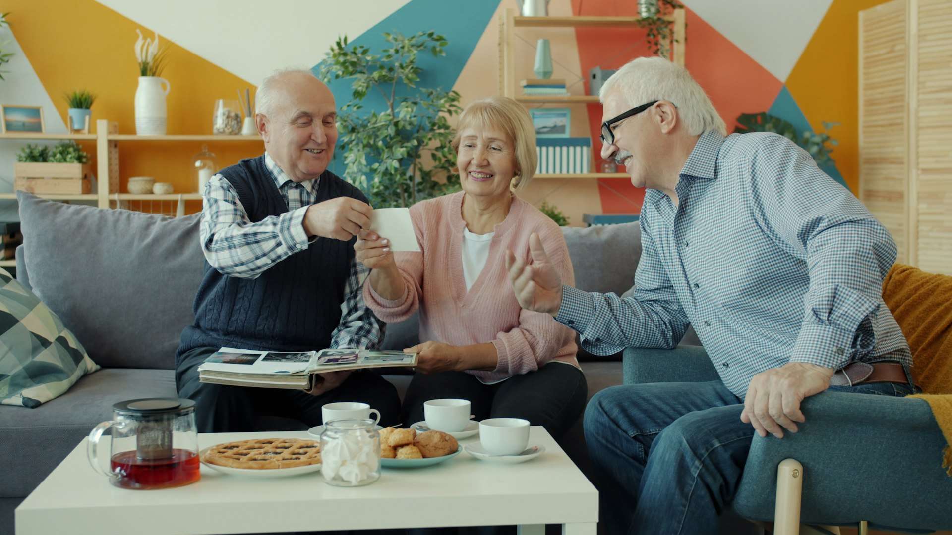 Three seniors smiling and reviewing paperwork together over tea at home