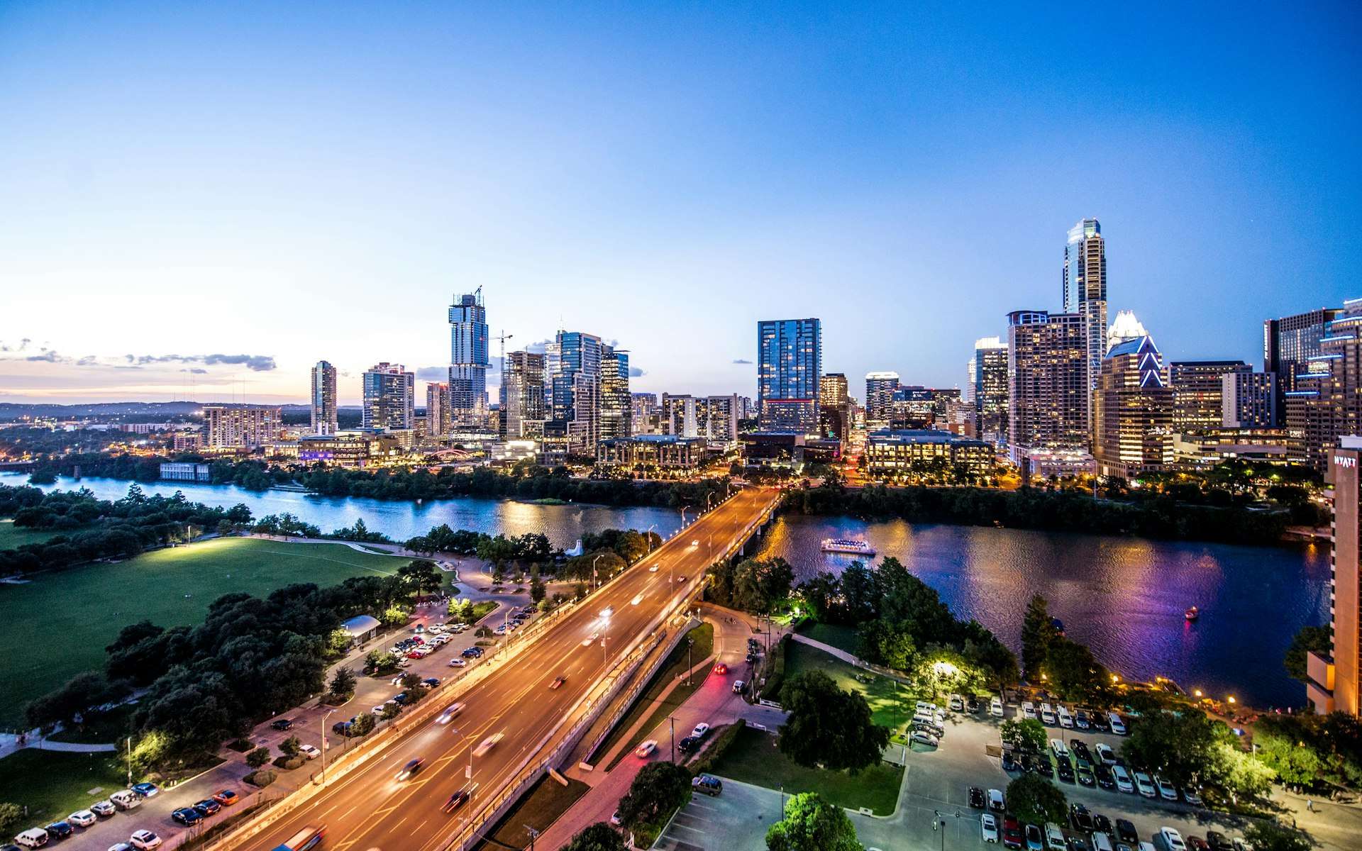 The Austin skyline at dusk with a bridge crossing the river in the foreground